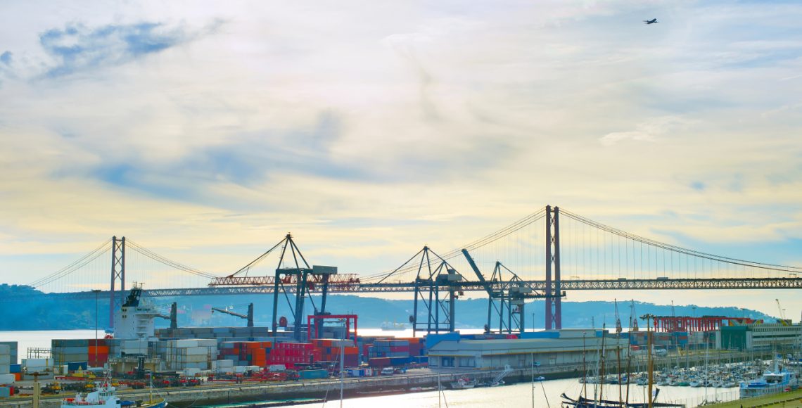 Plane flying over Lisbon commercial port. Portugal